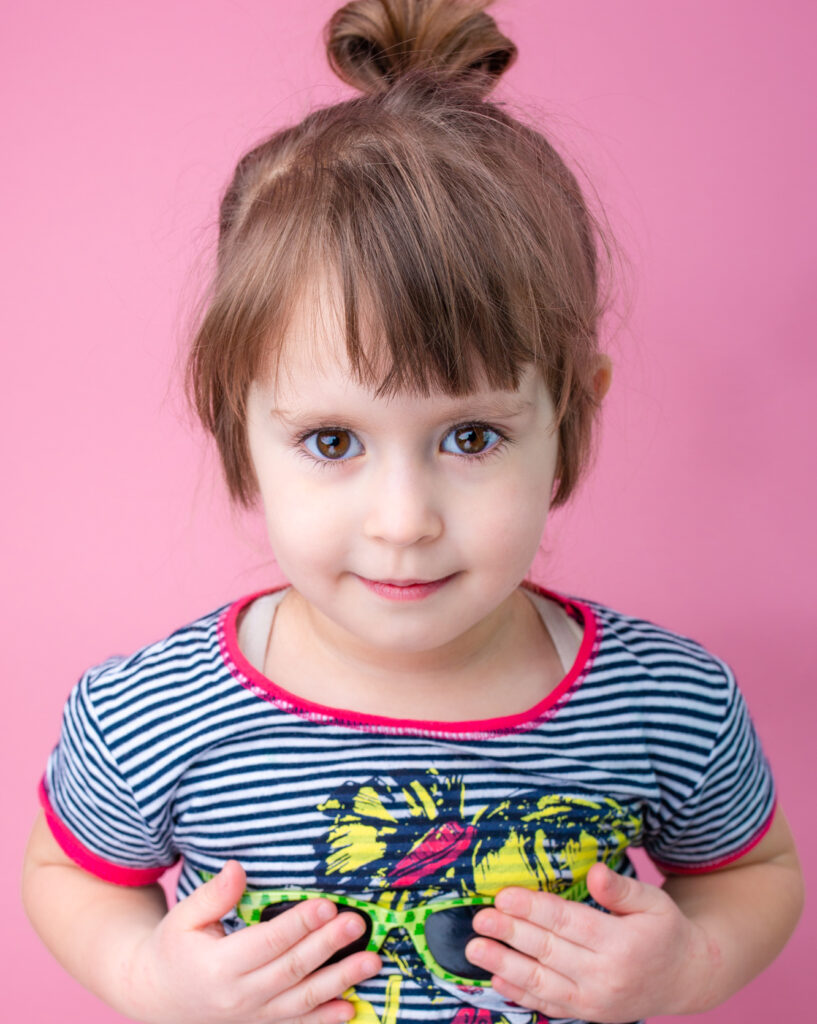 fun studio portrait toddler girl funny posing pink background summer portrait