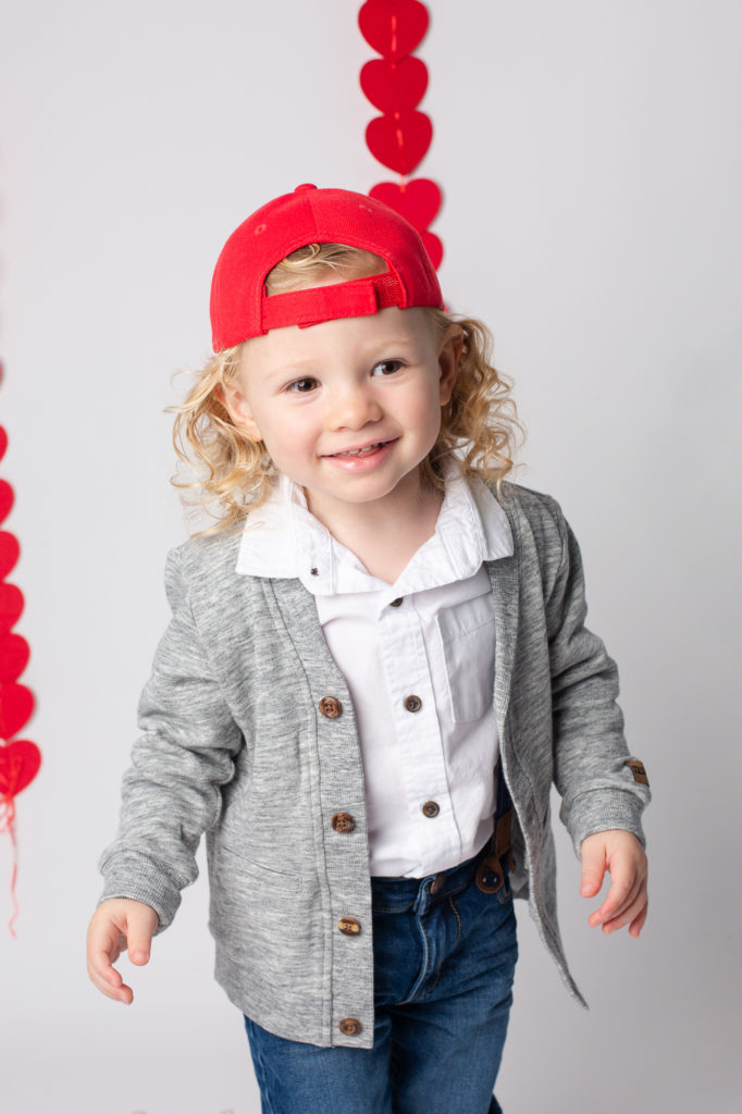 toddler boy in a red baseball hat hearts