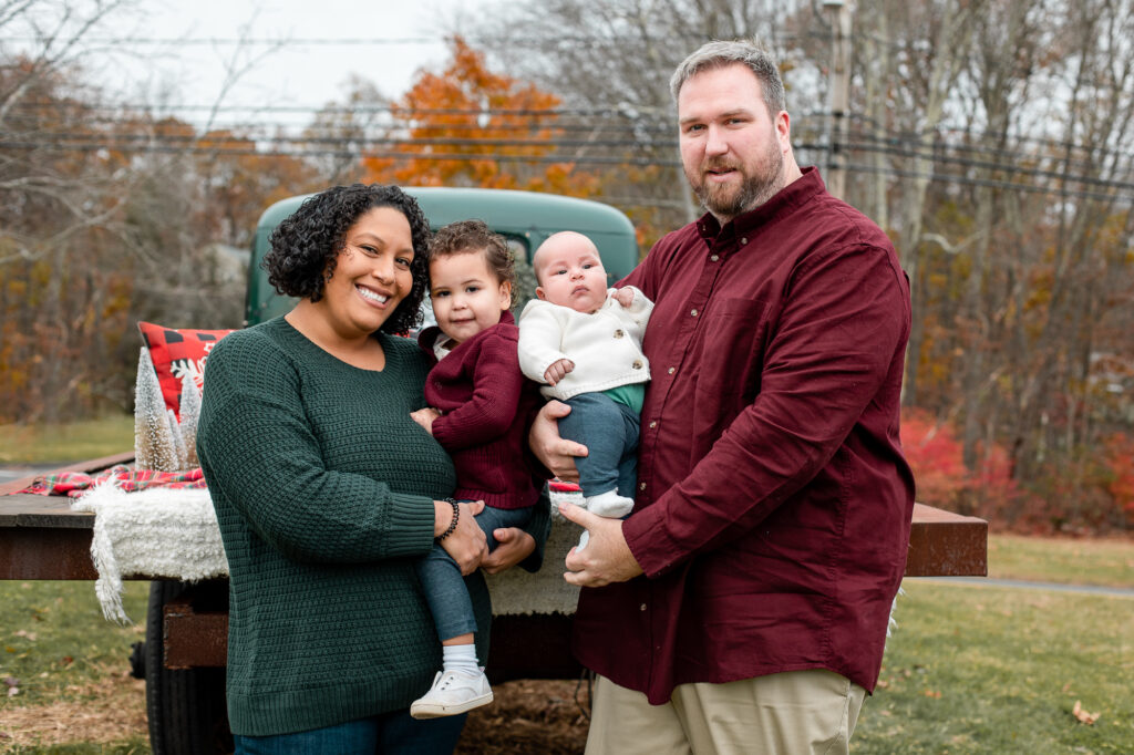 family of four Christmas session with a green truck on a farm