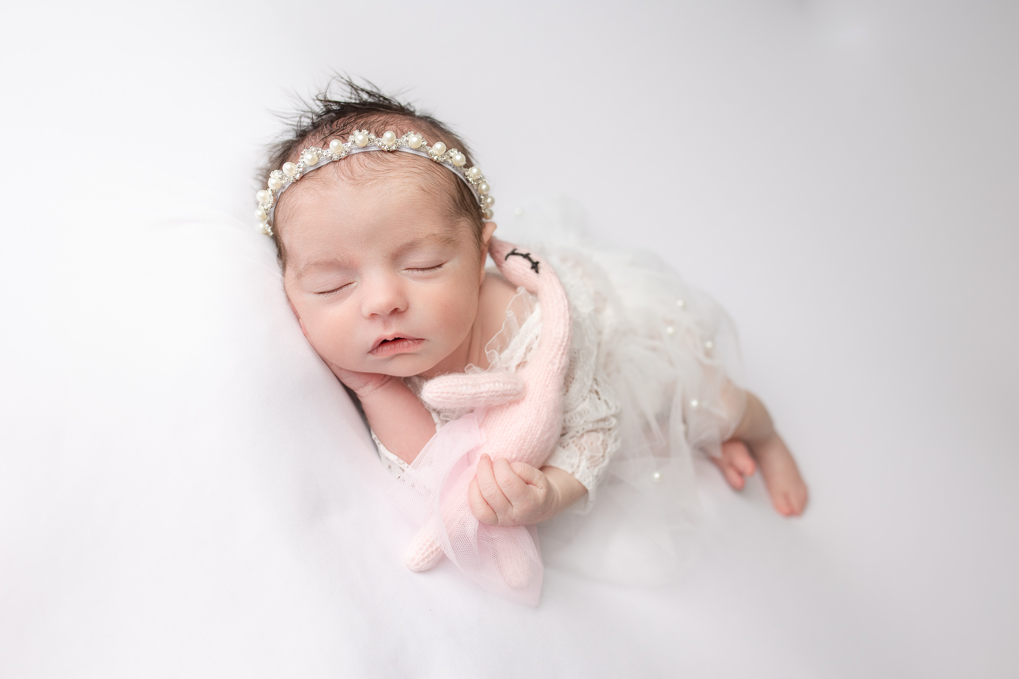 newborn photography baby girl in white posing Farmington ct side lying pose with a stuffed toy bird swan baby ballerina