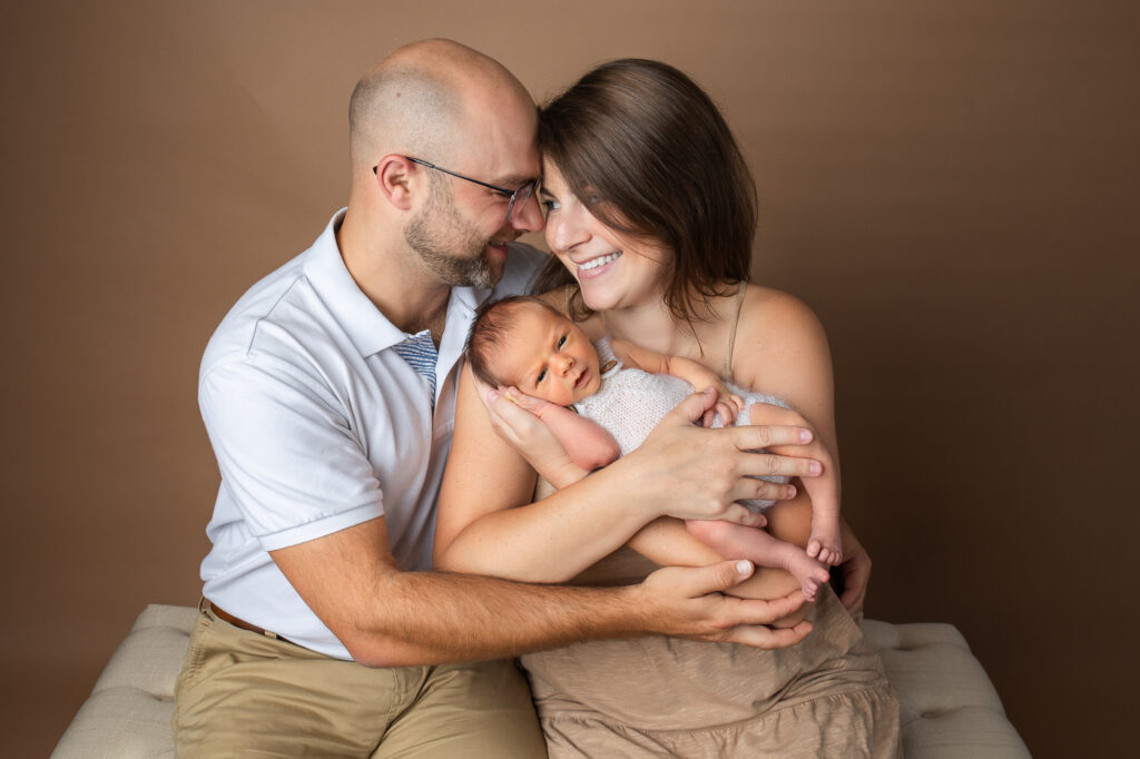 newborn posing with mom and dad, mocha brown backdrop savage, mom kissing newborn baby
