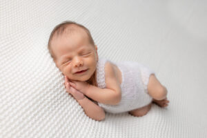 newborn baby boy smiling , all white, newborn photography