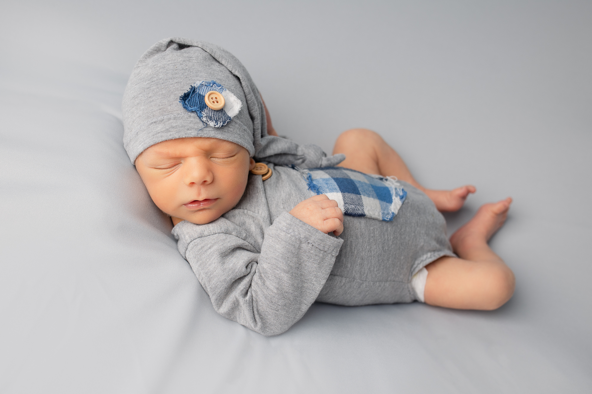 newborn baby boy in cute gray outfit hack Finn pose