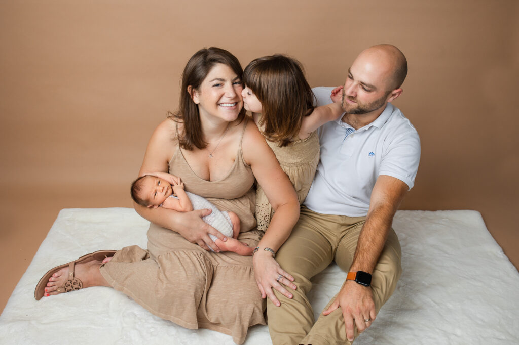 lifestyle candid newborn photography, studio family portraits, beige and brown, little girl kissing mom